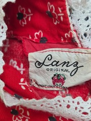 This vintage 1950s red dress features a Dutch heart print and delicate white lac
